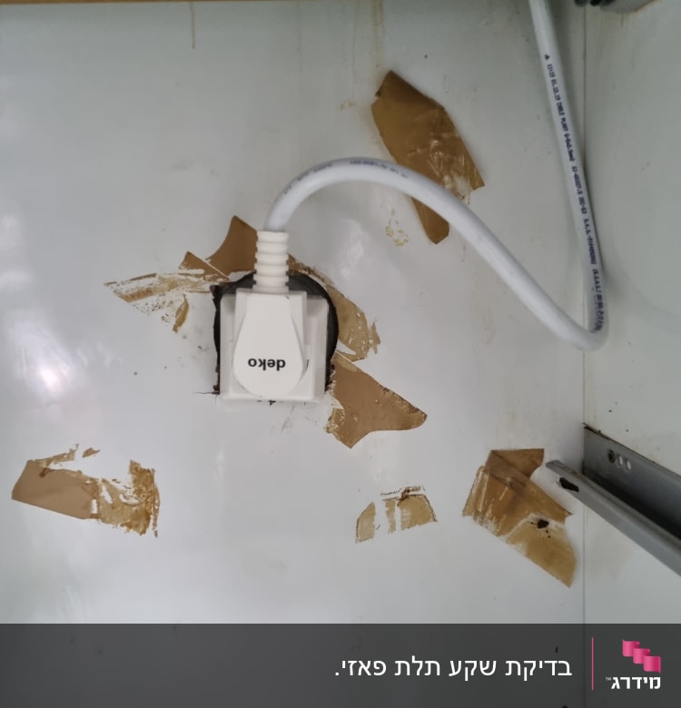 שקע חשמל עם כבל לבן בקיר לבן